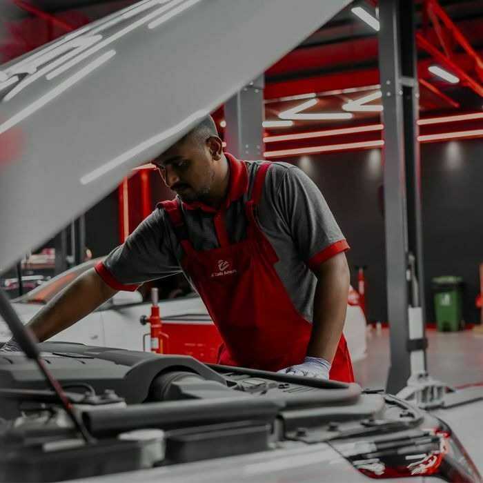 Al Zaabi Autocare technician inspecting an engine bay in the Mussafah workshop